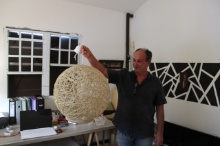 Michel dans son atelier avec une autre de ses créations, un lustre boule.